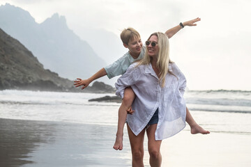 Happy family mother and son walking, playing, laughing on the beach. Mother hugging child. Enjoying life.
