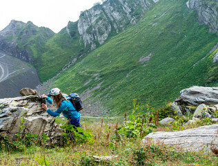 Young woman scientist ecologist zoologist setting up trap camera in nature reserve in mountains to...