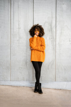 Trendy black woman in bright sweater on street