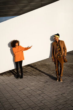 Modern black man and woman against white wall in sunset