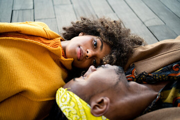 Sensual black couple in colorful clothes lying ace to face