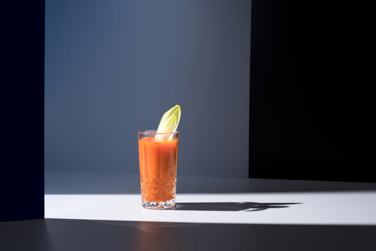 Vaso de jugo de zanahoria con hojas de endibia sobre fondo oscuro