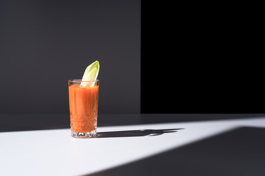 Vaso de jugo de zanahoria con hojas de endibia sobre fondo oscuro