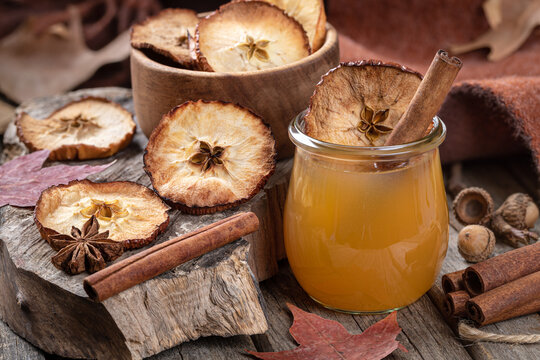 Glass of apple cider with cinnamon stick and dried apple chip