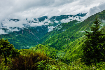 Obraz premium Hills in the Himalayas with green trees covered in mist and white clouds after a rainfall. Uttarakhand India.