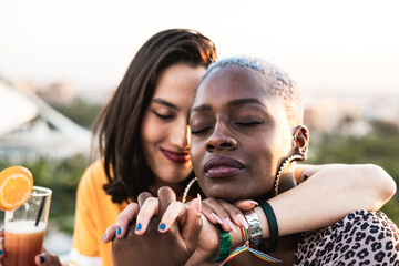 Multiracial lesbian couple sitting close together outdoors