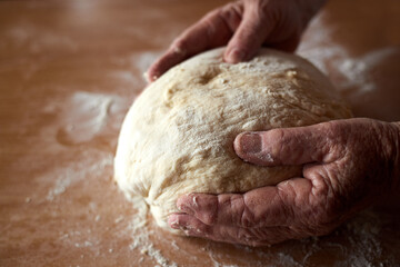 Grandmother's hands close-up prepare homemade dough.