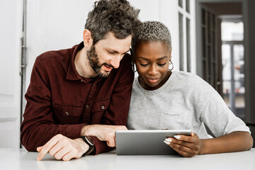 Positive multiethnic couple using digital tablet together