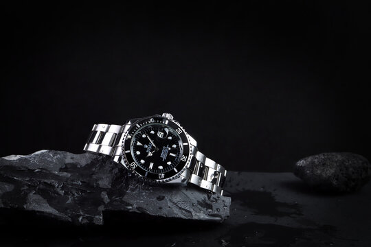 The Rolex vintage wristwatch ceramic bezel model black oyster perpetual submariner date 39 mm display on the wet rock stone table in the dark room and dark background