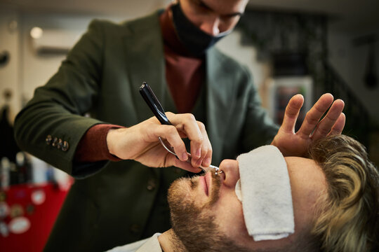 Barber shaving client in barbershop