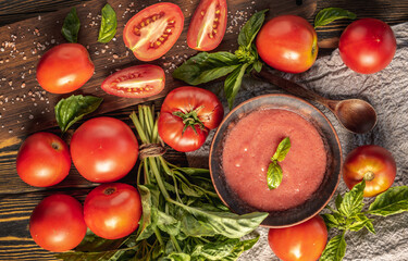 Ingredients for cooking an organic homemade sauce of tomatoes and basil on a wooden table. Top view