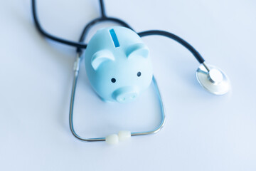 Piggy bank with stethoscope isolated on light blue background with copy space. Health care financial checkup or saving for medical insurance costs concept