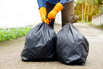 Closeup man holds black plastic bag that contains garbage inside. Concept : Waste management....
