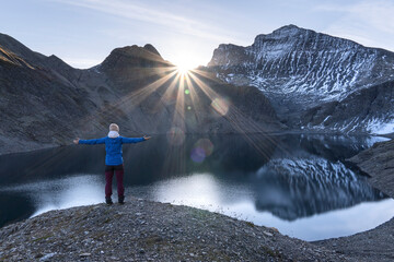 Female Hiker looking into sunrise over lake in Greina Plains, Grisons, Switzerland