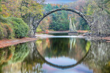 Astonishing autumn landscape in Azalea and Rhododendron Park Kromlau. Rakotz Bridge (Rakotzbrucke, Devil's Bridge)