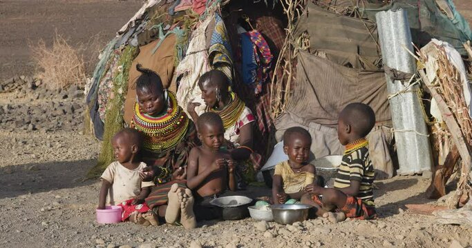 Close-up.Malnourished children due to extreme poverty, drought and climate change. Mother's and children eating maize porridge and fish infront of their dwelling.Kenya