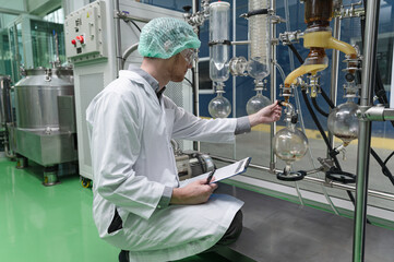 Inspector caucasian scientists use clipboard in the machine room extracting oil and cannabis seeds	