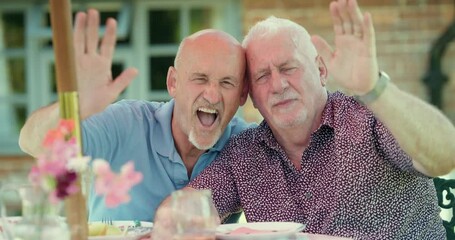 MS Smiling senior gay couple waving to camera in garden / East Sussex, UK