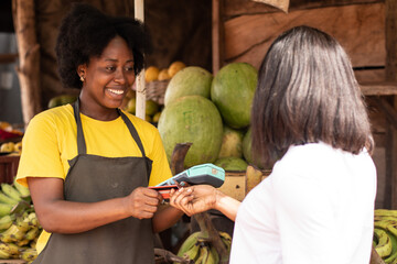 african women in a market, paying with credit card