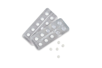 Two blisters with pills and five pills nearby on a white background