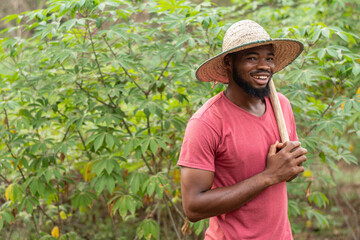 smiling african farmer carrying a hoe