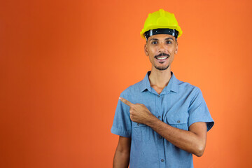 Engineers day - Black Man in Safety Helmet and Blue Shirt isolated on orange.