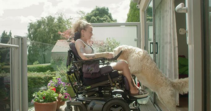 MS Woman in motorized wheelchair with dog on porch / Sheffield, UK