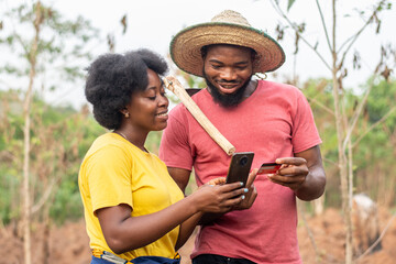happy african farmers using a phone and credit card