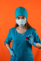 Fototapeta na wymiar nurse in blue uniform with mask gloves holding small red heart in operating room hospital.