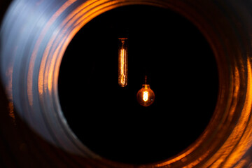 glowing bulbs with edison filament visible from the ventilation duct through the grate, the front and back background is blurred with bokeh effect