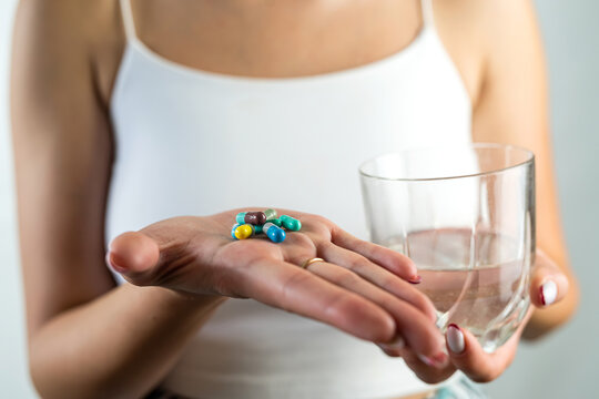 cropped photo of a beautiful young girl with a diet pill in one hand and a glass in the other.