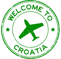 Grunge green welcome to Croatia word with airplane icon round rubber seal stamp on white background