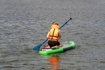 SUP surfboard. A young woman floats on a beautiful calm lake. The concept of summer holidays, travel, vacation, active and healthy life in harmony with nature. © Дмитри Лобакин