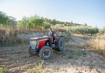 A farmer on a tractor drives around the farm field. Farm management skills and land works. Farming, agriculture. Rural farm.