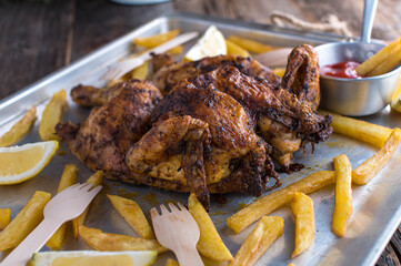 Crispy Spatchcock chicken with french fries on a baking tray