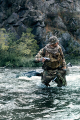 Vertical photo of a mercenary soldier crossing the river after the completion of the sabotage...