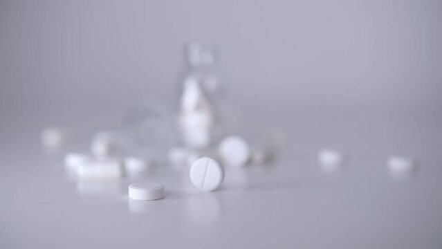 movement of a white pill on the table against the bg of other pills and jars