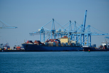 Fototapeta premium ROTTERDAM, THE NETHERLANDS - New container terminal with a very large container ship and in the foreground a smaller inland container ship on the Maasvlakte of the port of Rotterdam