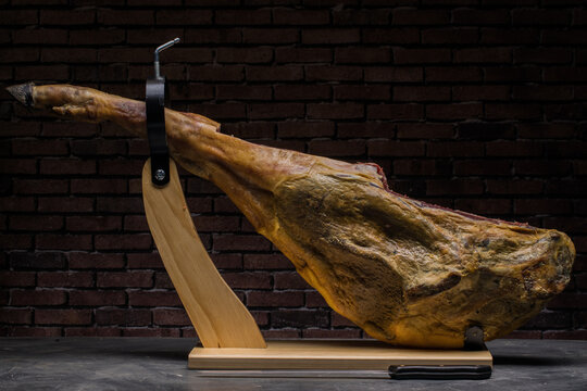 Ham in sack on wooden stand on black background