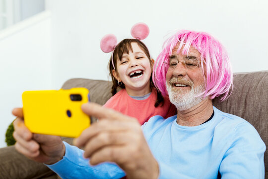 Grandfather In Glasses And Wig Taking Selfie With Kid
