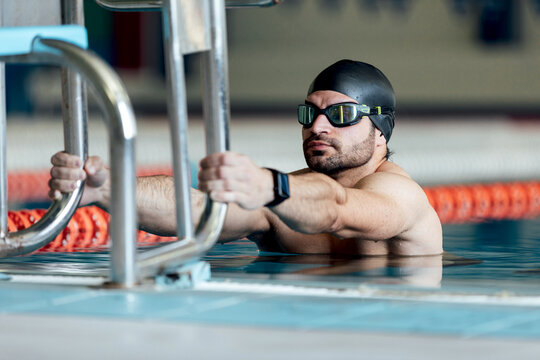 Swimmer in goggles and cap exercising in pool