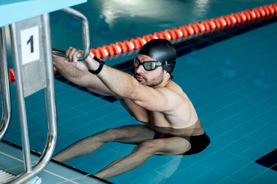 Swimmer in goggles and cap exercising in pool