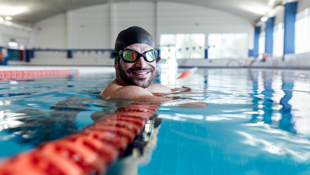 Smiling swimmer leaning on lane divider in pool