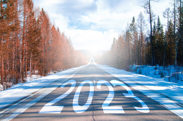 The word 2023 written on highway road in the middle of empty asphalt road at dawn and beautiful...