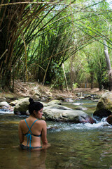 Girl on vacation in a spa. Girl bathing in a river. Woman with hat. River with stones and bamboo