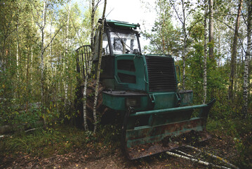 Crane forwarder machine during clearing of forested land. Wheeled harvester transports raw timber from felling site out. Harvesters, Forest Logging machines. Forestry forwarder on deforestation.