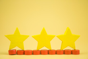 Three wood yellow star shape rating for user reviews. Three yellow ranking stars. Customer satisfaction is rated highest for outstanding company services. Concept of a satisfaction survey.