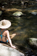 Girl on vacation in a spa. Girl bathing in a river. Woman with hat. River with stones and bamboo