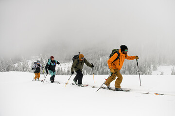 Group of male skiers with backpacks hiking on skis in snow. Skitour concept.