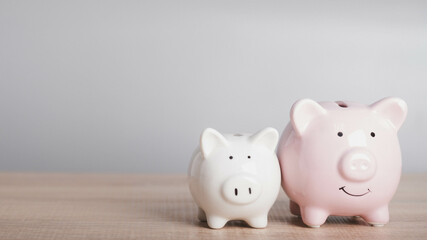 Two Piggy bank on wood table in gray background with copy space for text. Growth, saving budget and financial investment for retirement rich concept.